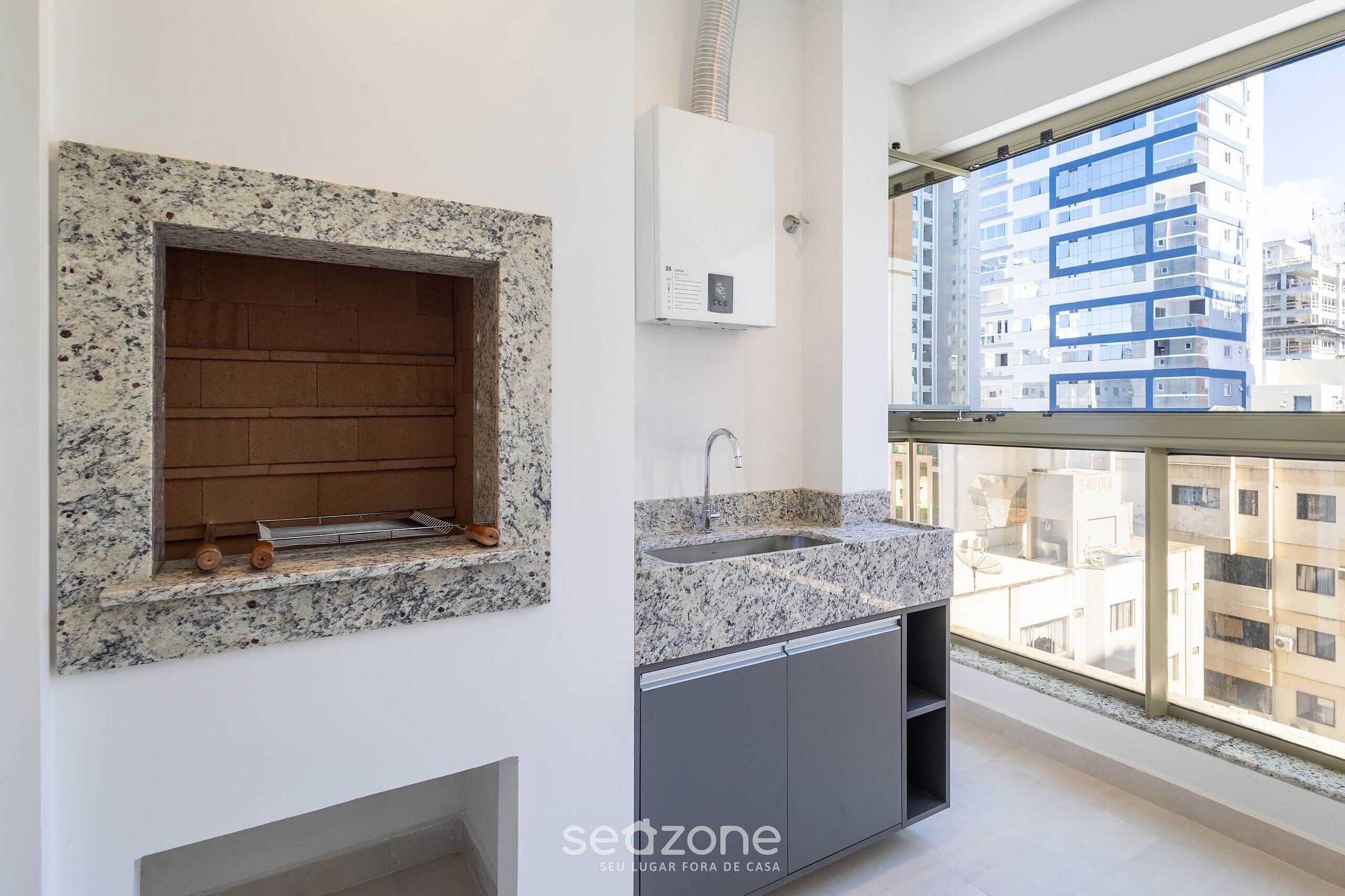 A modern kitchen with a built-in stove, a sink, and a window overlooking a cityscape.