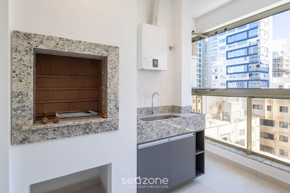 A modern kitchen with a built-in stove, a sink, and a window overlooking a cityscape.