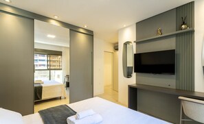 A modern hotel room with a bed, a desk, a TV, and a wardrobe. - Apt w/ Gourmet Balcony 550m From the Beach Lle0204 (Itapema)