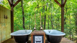 Two black bathtubs on a wooden deck with a sign between them. - Sasquatch soak shack (Mena)