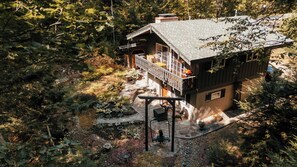 Een chalet met balkon, omringd door dicht bos.