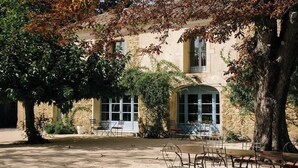 Un edificio de piedra con un patio, bancos y un árbol.