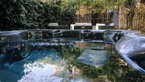 Un jacuzzi con asientos alrededor, rodeado de follaje.