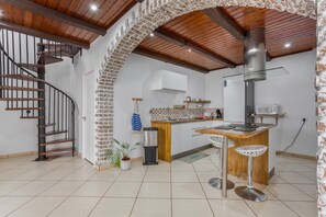 Una cocina con una isla central, una escalera de caracol y una pared de ladrillo.