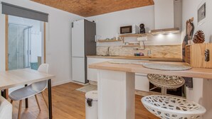 A modern kitchen with a wooden ceiling, white cabinetry, a microwave, and a sink.