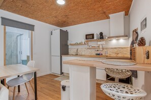 A modern kitchen with a wooden ceiling, white cabinetry, a microwave, and a sink.