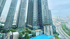 A high-rise building with a modern glass facade, surrounded by other tall buildings, and a pool area with palm trees. - The Landmark 81 Deluxe Apartment Suite (Ho Chi Minh City)