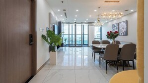 A modern hotel lobby with a dining area, large windows, and a chandelier. - The Landmark 81 Deluxe Apartment Suite (Ho Chi Minh City)