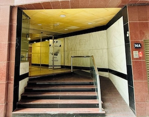Un escalier menant à un hall d’entrée doté d’une porte en verre, d’une enseigne indiquant « Vision Mission » et d’un détecteur d’incendie fixé au mur.