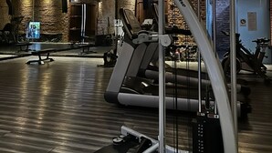 Ein Fitnessraum mit Trainingsgeräten, Backsteinwänden und Holzbalken an der Decke.