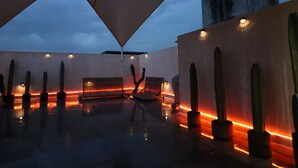Eine Dachterrasse mit geometrischem Design, mit einer Sitzgruppe in der Mitte und mehreren Pflanzgefäßen.