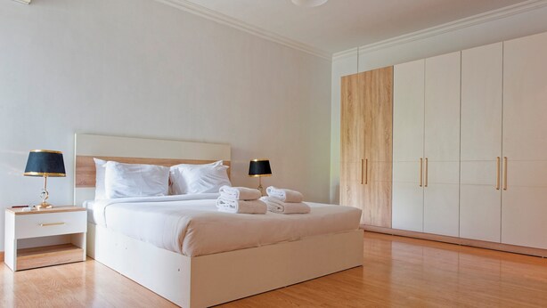 Un dormitorio moderno con una cama grande, mesitas de noche y un armario.