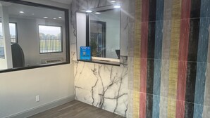 A bathroom with a marble wall, a mirror, a window, and a colorful striped wall. - Motel 6 Dallas, Tx – St. Augustine / Hwy 175 (Dallas)