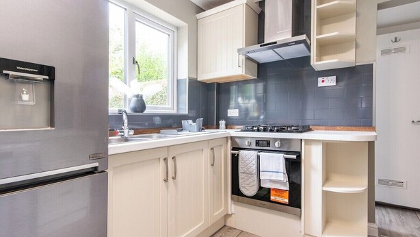 A modern kitchen with a built-in water dispenser, a stove, oven, and white cabinetry.