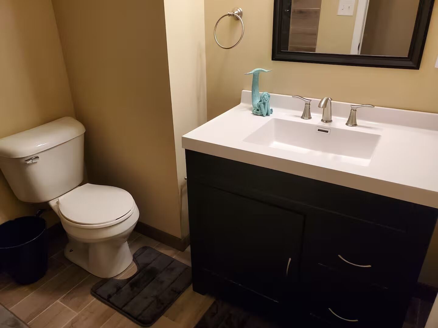 A bathroom with a toilet, sink, and mirror.