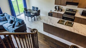 Et moderne køkken med marmorbordplade, indbygget ovn og et spiseområde med bord og stole.
