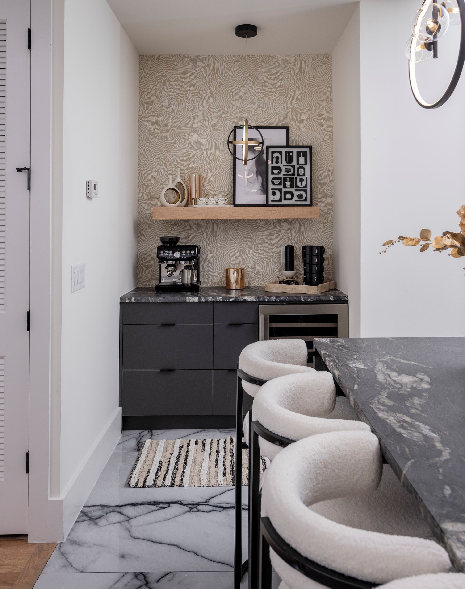 A compact kitchen with a coffee machine, a small countertop, and a dining area with bar stools.