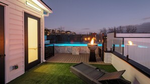 En baghave med swimmingpool, bålsted og træterrasse.