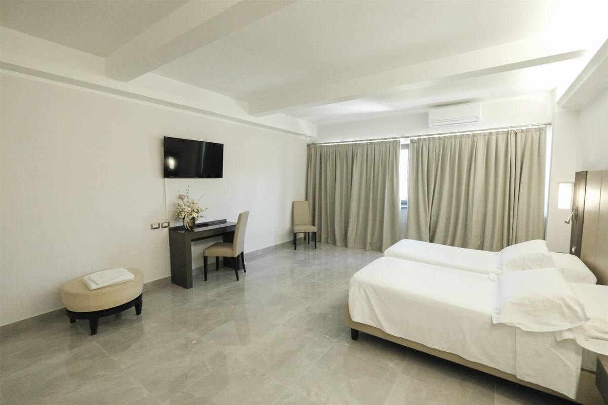 A hotel room with a bed, a desk, a chair, and a TV mounted on the wall.