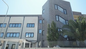 A modern building with a mix of rectangular and angular designs, featuring multiple windows and a prominent corner structure.