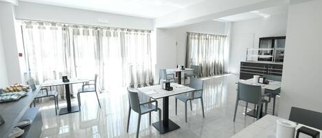 A modern hotel dining area with a long table, chairs, and a buffet on one side.