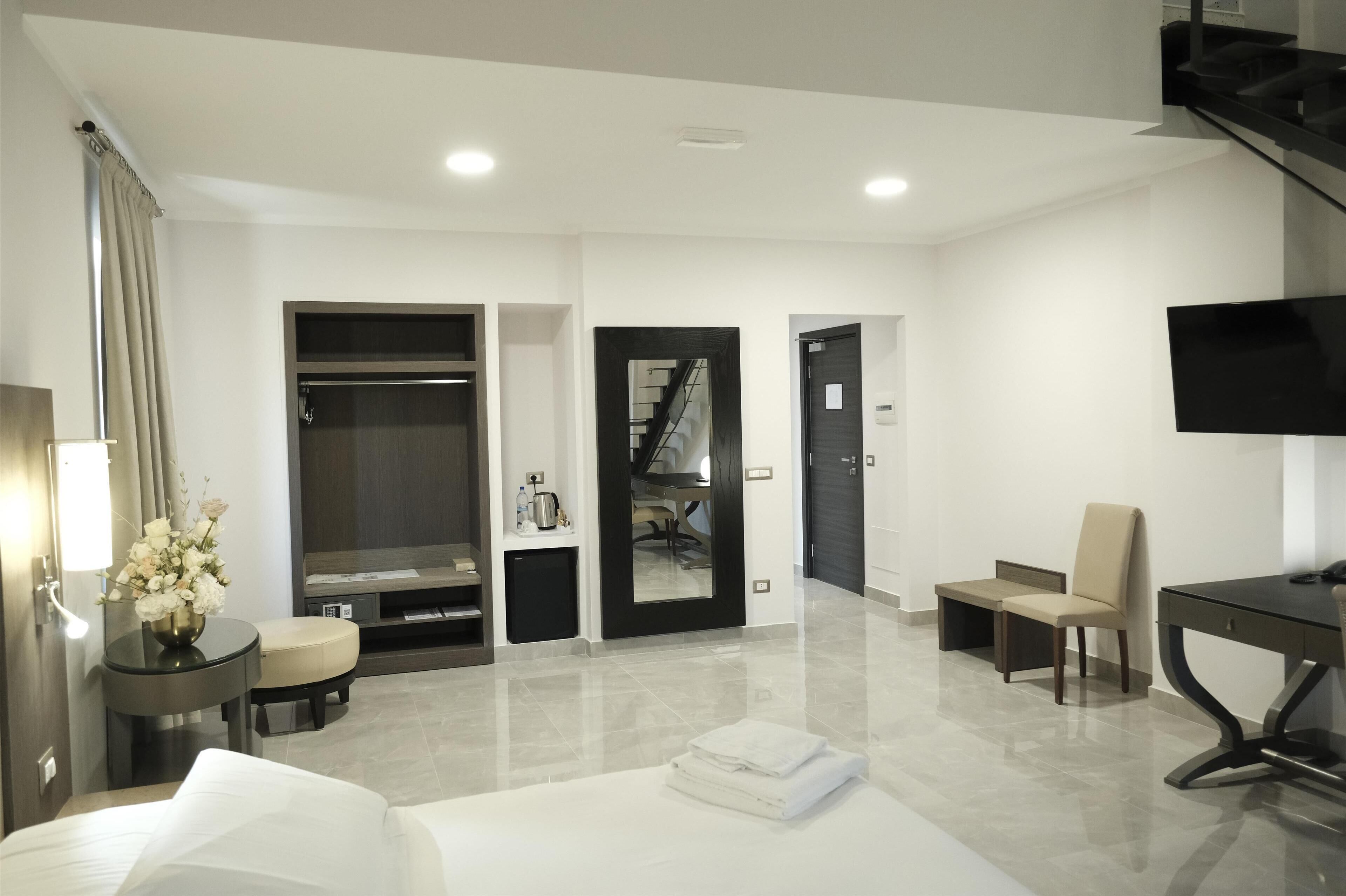 Una habitación de hotel moderna con una cama, un escritorio, una silla, un televisor, un armario y una escalera.