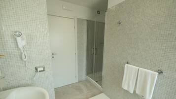 A bathroom with a white sink, a glass shower enclosure, and a towel rack with two towels.