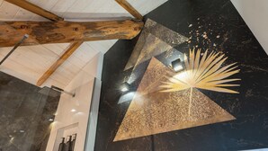 A modern interior with a black and gold geometric wall art piece, wooden beams, and a bathroom with marble tiles. - 4 Elements - Italian GuestHouse (Calolziocorte)