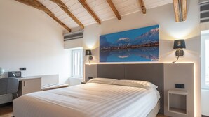 A bedroom with a large bed, wooden ceiling beams, a cityscape painting, bedside lamps, and a desk with a globe and radio. - 4 Elements - Italian GuestHouse (Calolziocorte)