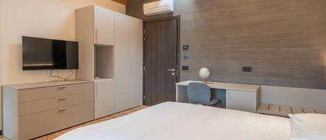 Een moderne slaapkamer met een groot bed, een televisie, een bureau met een wereldbol en een garderobe.