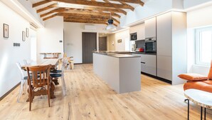 A modern kitchen with wooden beams, a central island, and stainless steel appliances. - 4 Elements - Italian GuestHouse (Calolziocorte)