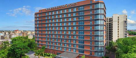 A multi-story hotel with a prominent 'Four Points' sign, a covered entrance, and a view of the surrounding urban area.