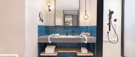 A modern bathroom with a dual sink vanity, a large mirror, wall-mounted towel racks, and a shower area.