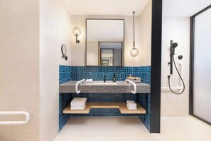 A modern bathroom with a dual sink vanity, a large mirror, wall-mounted towel racks, and a shower area. - Four Points By Sheraton Haikou International Airport (Haikou)