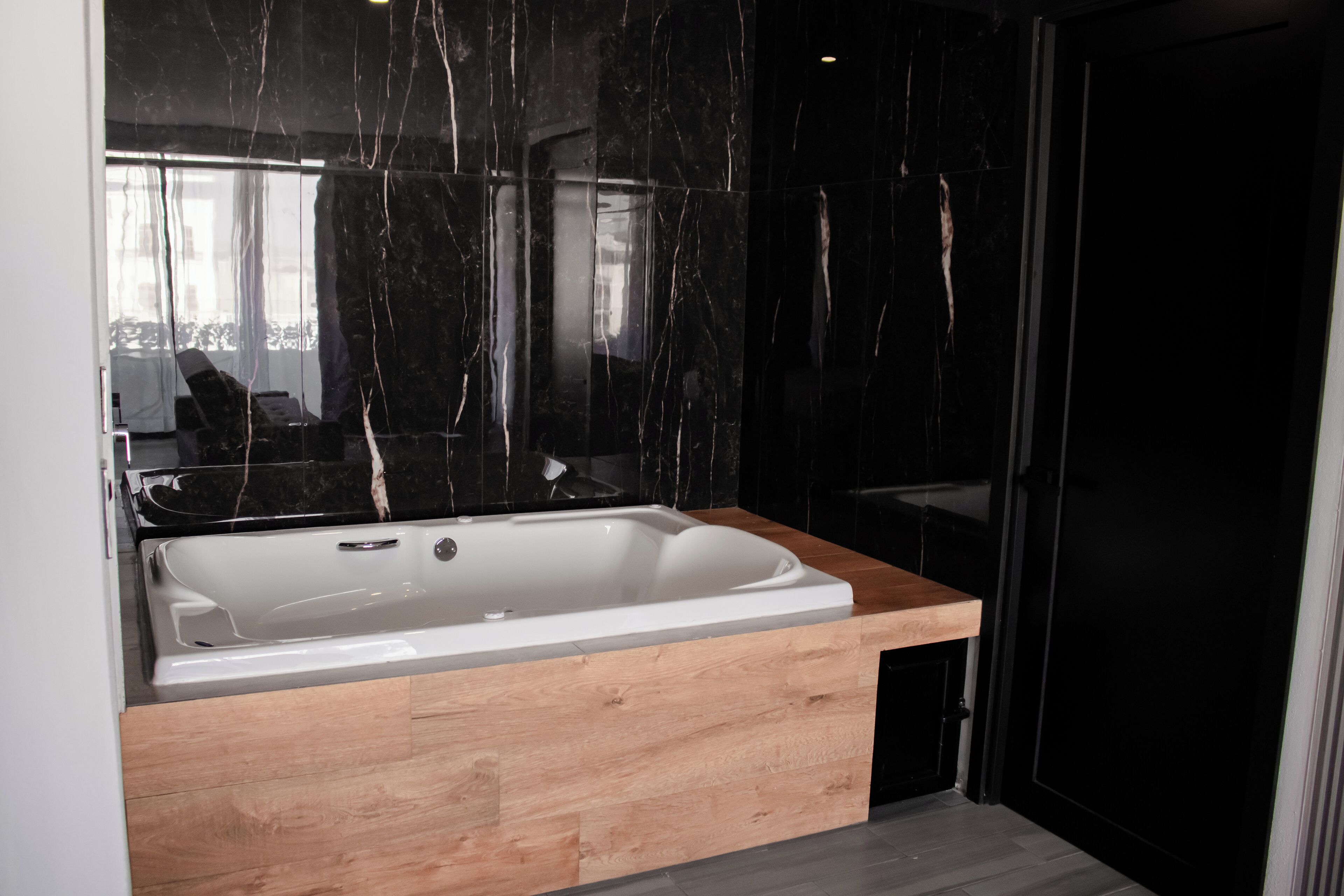 A modern bathroom with a freestanding bathtub, wooden vanity, and a large mirror.