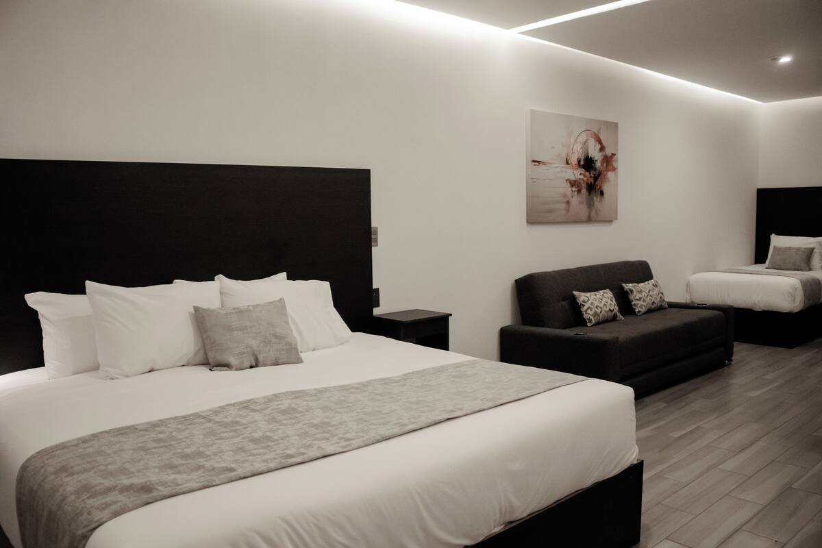 Une chambre d’hôtel moderne avec un grand lit, un canapé et une petite table.
