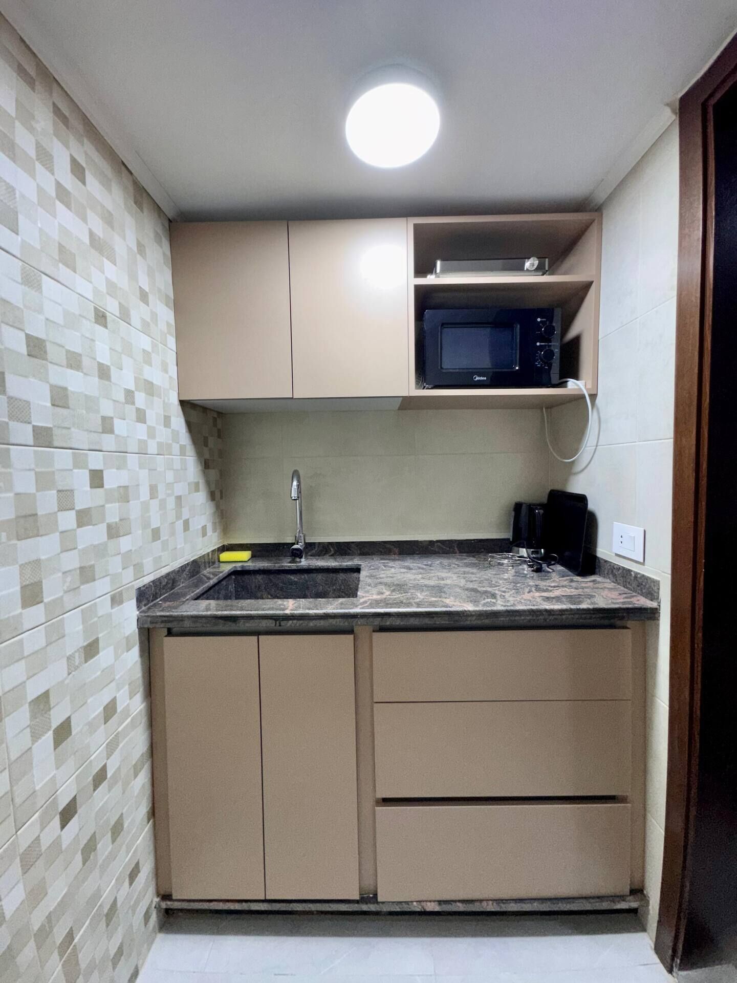 A compact kitchen with a built-in microwave, a sink, and a countertop.