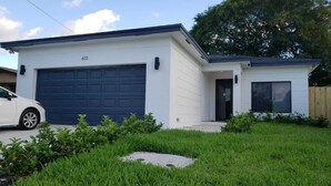 A modern single-story house with a garage, a front door, and a small porch. - Enjoy our brand new home close to Hollywood in Hallandale Beach! (Hallandale Beach)