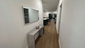 A hallway with a patterned console table, a large mirror, and a dining area in the background. - Enjoy our brand new home close to Hollywood in Hallandale Beach! (Hallandale Beach)