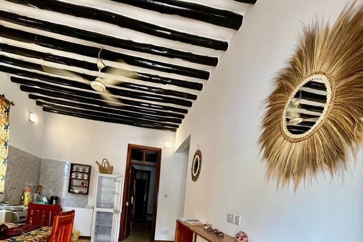 Un comedor con un banco de madera, una mesa con sillas y un techo con vigas a la vista.