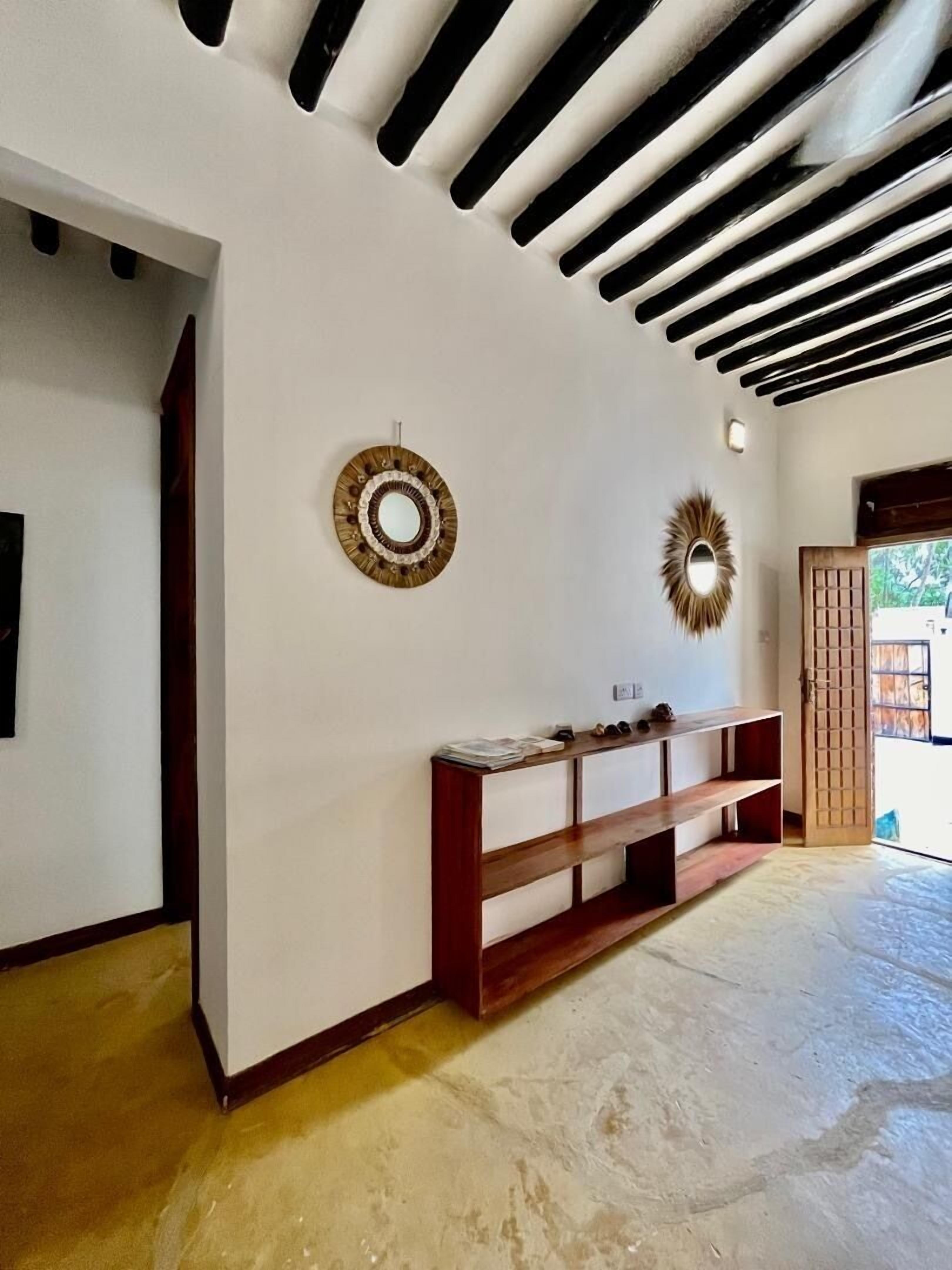 A hallway with a wooden bench, a wall-mounted mirror, and a door leading outside.