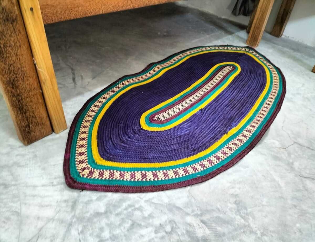 A circular rug with a multicolored pattern, placed on a marble floor.