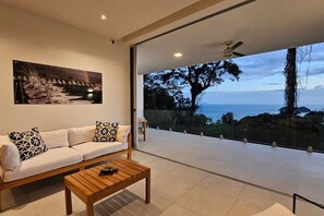 Un soggiorno moderno con divano, tavolino da caffè e una grande finestra vista mare.
