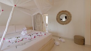 A bedroom with a canopy bed, a round mirror, and a small round seating area. - Ndoto House in Rafiki Tamu Dunia Resort (Watamu)
