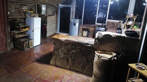 Une cuisine rustique avec des plans de travail en pierre, un évier en pierre et une table en bois.