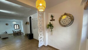 A spacious living area with a wooden floor, a dining table with chairs, a black heater, and a decorative white partition. - House with terrace and views. Brand new in the middle of nature (Chelva)