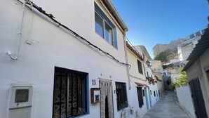 A narrow street with buildings painted white and blue, featuring numbered doors and windows with metal bars. - House with terrace and views. Brand new in the middle of nature (Chelva)