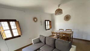 A living room with a sectional sofa, a dining table with chairs, and a ceiling light fixture. - House with terrace and views. Brand new in the middle of nature (Chelva)