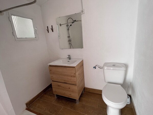 A bathroom with a wooden vanity, a white sink, a mirror, a shower, and a toilet. - House with a terrace and a view. Brand-new, right in the heart of nature (Chelva)
