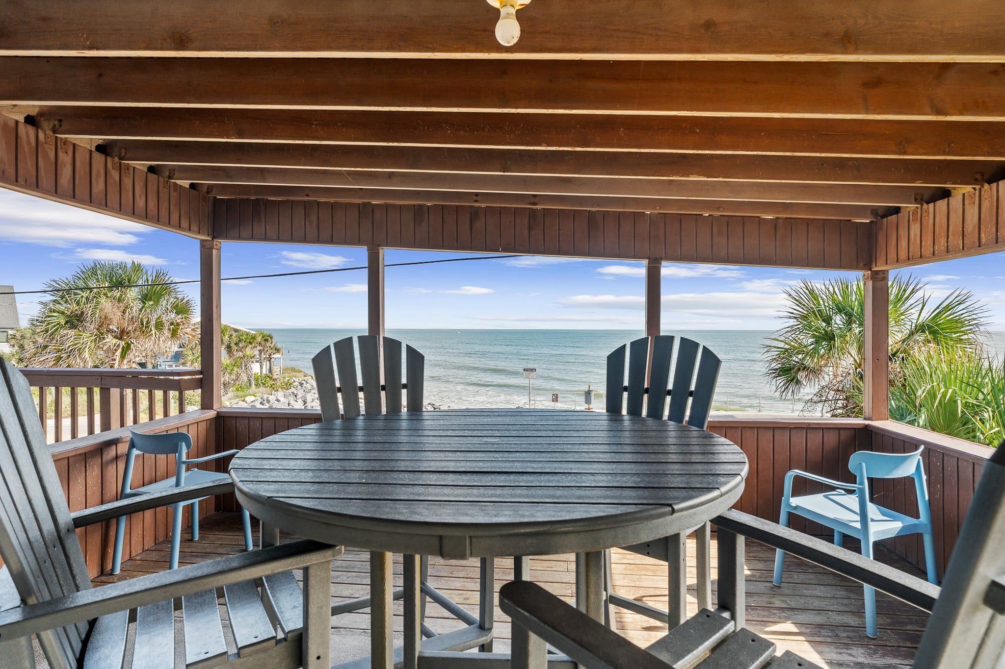 A covered outdoor seating area with a view of the ocean.